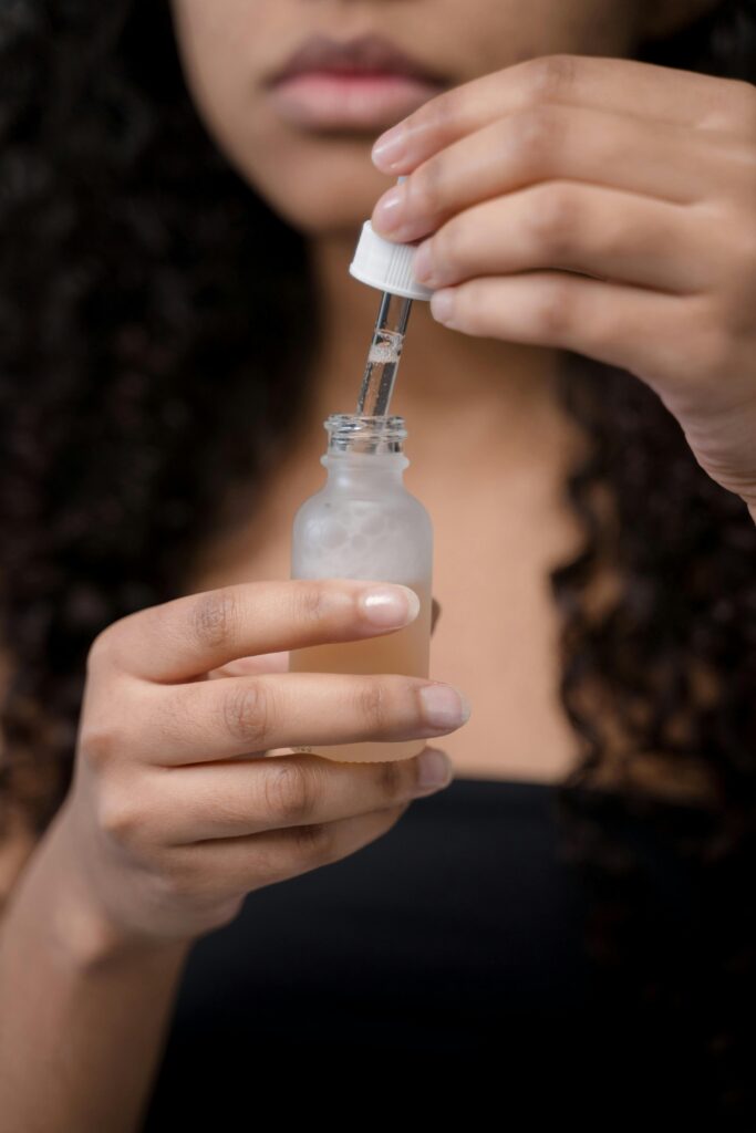 Detail shot of woman applying skincare serum with dropper.
